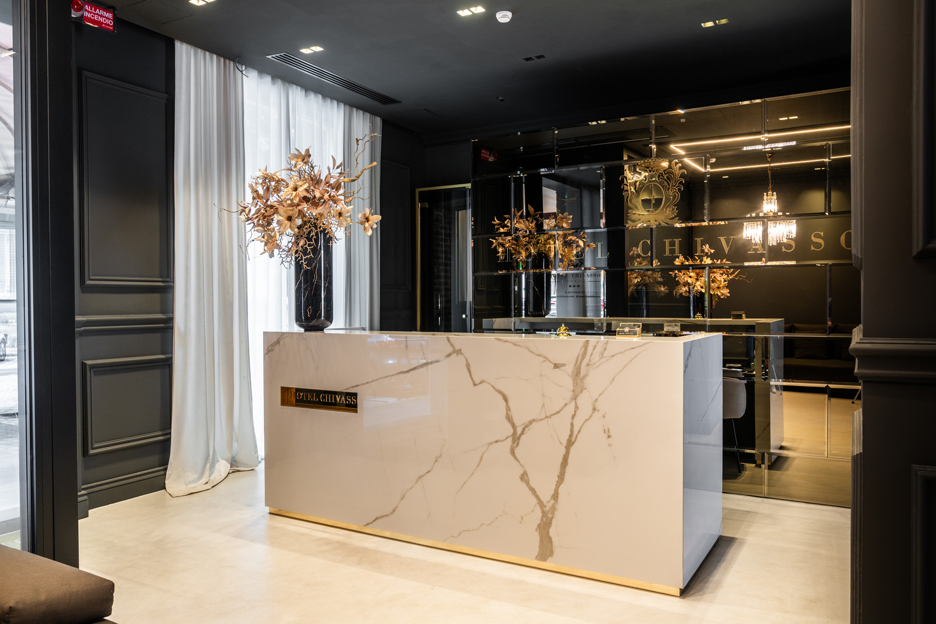 Reception dell'Hotel Chivasso con bancone in marmo e logo dorato